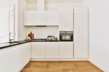 Minimalist tarzı beyaz mobilyalı, lavabolu ve sobalı bir ev mutfağı.