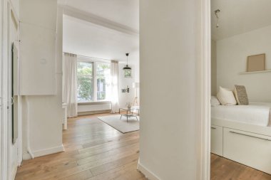 Çağdaş dairenin geniş odasındaki dinlenme odası ve mutfağın yakınındaki sandalyeli ve çiçekli masa.