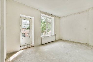 Evdeki boş ışık odasında, beyaz duvardaki plastik pencere ve radyatör.