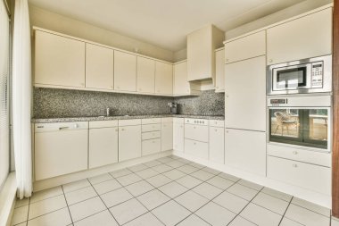 Pencereleri ve ahşap parke zemini olan boş beyaz mutfağın içi.