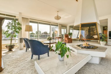 Lüks bir ev tasarımı. Yanan şömineli rahat bir oturma odası. Gün ışığında rahat bir kanepe ve halı.