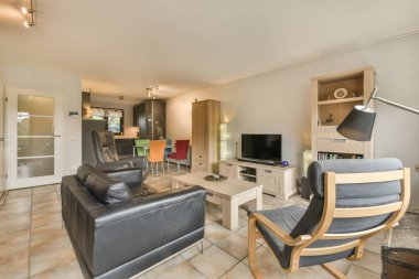 Beyaz oturma odasında kanepe ve televizyonlu siyah mutfak planı.