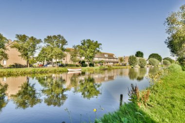 Arabaları, ağaçları ve fenerleri olan boş bir kaldırımdan panorama manzaralı evler.
