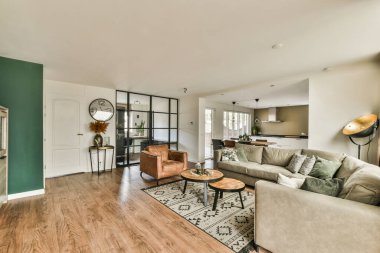 Çağdaş dairenin geniş odasındaki dinlenme odası ve mutfağın yakınındaki sandalyeli ve çiçekli masa.