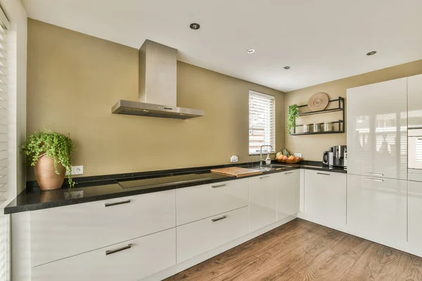 Interior of contemporary kitchen with stylish black and white cupboards and appliances near dining area in contemporary apartment