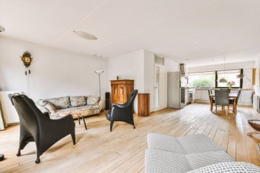 Günümüz minimalist tasarımı. Hafif stüdyo dairesinin ahşap masası ve oturma odası ile beyaz duvarları ve parke zemini arasında yemek masası ve sandalyeleri var.