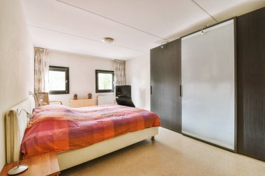 Yatak odasının iç tasarımı, yatak odası ve ahşap gardırop modern dairenin penceresinin kenarına yerleştirilmiş.