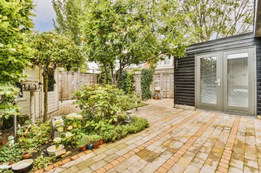 Oturma alanı ve ahşap çitlerin yanındaki küçük bahçesi olan düzgün asfaltlı bir avlu.