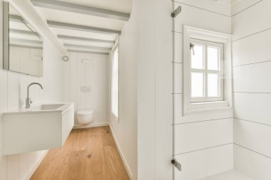 Evdeki modern tuvalette asılı duran banyo musluğu ile duvar arasındaki cam bölme.