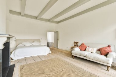 Rahat yatak ve şömine, modern apartmanda beyaz duvarları ve televizyonu olan minimalist tarzda bir yatak odasına yerleştirildi.