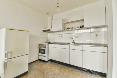 Ev aletleri ve dolaplarla döşenmiş rahat, açık bir mutfak.