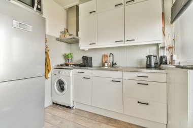 Çağdaş dairenin geniş odasındaki dinlenme odası ve mutfağın yakınındaki sandalyeli ve çiçekli masa.