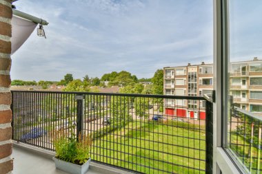 Küçük balkondan park edilmiş binaların ve ağaçların panoramik görüntüsü