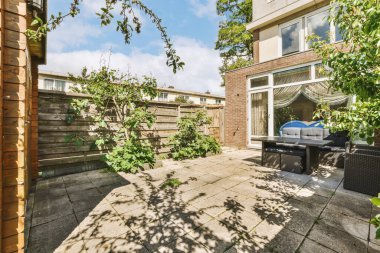 Oturma alanı ve ahşap çitlerin yanındaki küçük bahçesi olan düzgün asfaltlı bir avlu.