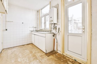 İyi organize edilmiş küçük bir ev mutfağı pencerenin altında lavabo, sobalı hafif mobilyalar ve kentsel apartmanda buzdolabı var.
