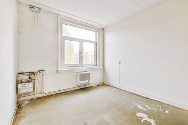 Evdeki boş ışık odasında, beyaz duvardaki plastik pencere ve radyatör.