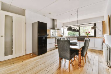 Günümüz minimalist tasarımı. Hafif stüdyo dairesinin ahşap masası ve oturma odası ile beyaz duvarları ve parke zemini arasında yemek masası ve sandalyeleri var.