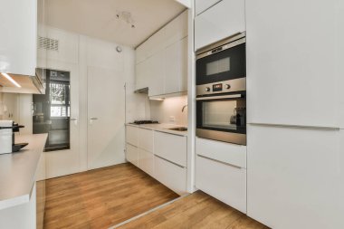 Çağdaş dairenin geniş odasındaki dinlenme odası ve mutfağın yakınındaki sandalyeli ve çiçekli masa.