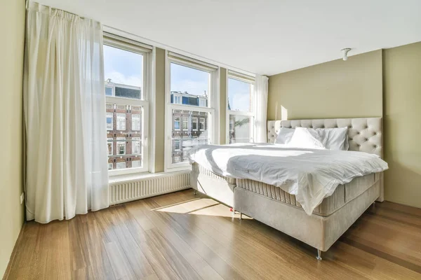クイーンサイズベッドと大きな窓に対する食器棚付きの光の寝室のインテリア — ストック写真