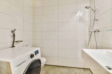 Banyoda beyaz fayanslı duvarlar ve lavabonun yanında açık duş var.