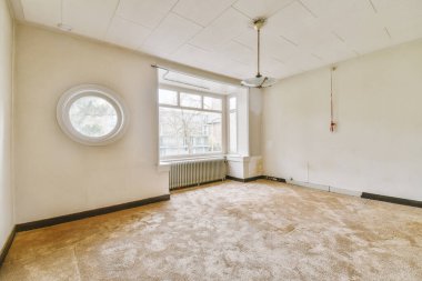 Evdeki boş ışık odasında, beyaz duvardaki plastik pencere ve radyatör.