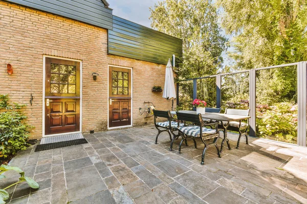 Neat paved patio with sitting area and small garden near wooden fence