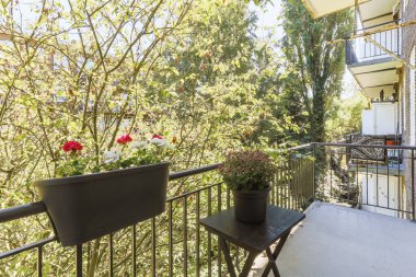 Narrow brick balcony with metal railings, wooden chair and door