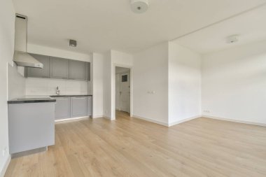 Pencereleri ve ahşap parke zemini olan boş beyaz mutfağın içi.