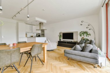 Günümüz minimalist tasarımı. Hafif stüdyo dairesinin ahşap masası ve oturma odası ile beyaz duvarları ve parke zemini arasında yemek masası ve sandalyeleri var.