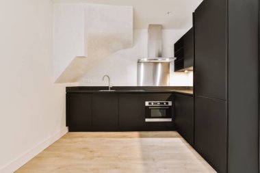 Minimalist tarzı beyaz mobilyalı, lavabolu ve sobalı siyah dar bir ev mutfağı.