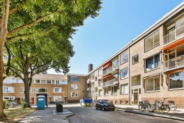 Arabaları, ağaçları ve fenerleri olan boş bir kaldırımdan panorama manzaralı evler.