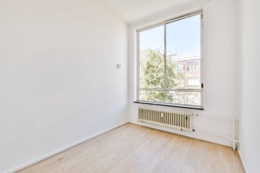 Evdeki boş ışık odasında, beyaz duvardaki plastik pencere ve radyatör.