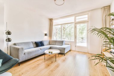 Çağdaş dairenin pencerelerine karşı rahat kanepesi ve televizyonu olan oturma odası.