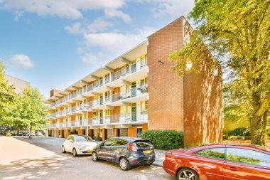 Arabaları, ağaçları ve fenerleri olan boş bir kaldırımdan panorama manzaralı evler.