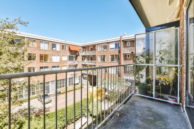 Dar tuğlalı balkon, metal parmaklıklar ve kapı.