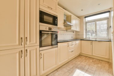 Modern ev mutfağı iç tasarımı beyaz dolaplar, dolaplar ve çelik kapüşon ile çağdaş apartmanda.