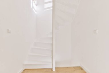 Minimalist iç tasarımı olan modern lüks dairenin ikinci katına çıkan ahşap merdivenli beyaz koridor.