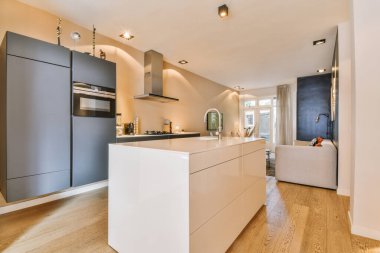 Geniş, boş bir stüdyo dairenin iç tasarımı. Geniş pencereleri, kaplaması ve mutfak setiyle döşenmiş beyaz duvarları var.