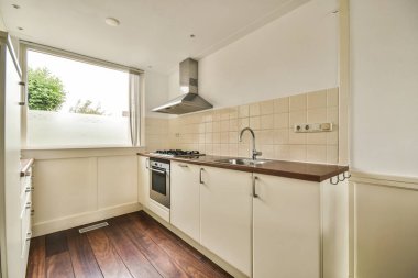 Modern dairenin yemek alanı yakınındaki şık beyaz dolapları ve aletleri olan çağdaş mutfağın içi.