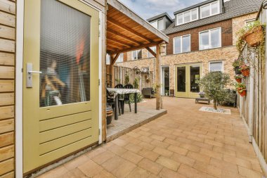 Oturma alanı ve ahşap çitlerin yanındaki küçük bahçesi olan düzgün asfaltlı bir avlu.