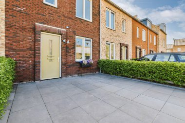 Tabelaları, arabaları, kaldırımları ve ahşap kapıları olan tuğla binanın önü daireye çıkıyor.