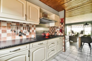 Çağdaş dairenin geniş odasındaki dinlenme odası ve mutfağın yakınındaki sandalyeli ve çiçekli masa.