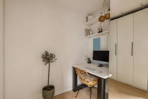 木の机と食器棚の近くの棚付きの光の家のオフィスのインテリア — ストック写真