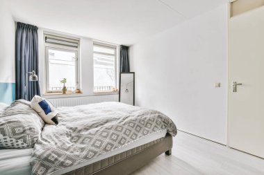 Beyaz duvarları, yumuşak rahat yatağı ve aydınlatmalı minimalist tarzı rafları olan küçük Mansard yatak odasının modern iç tasarımı.