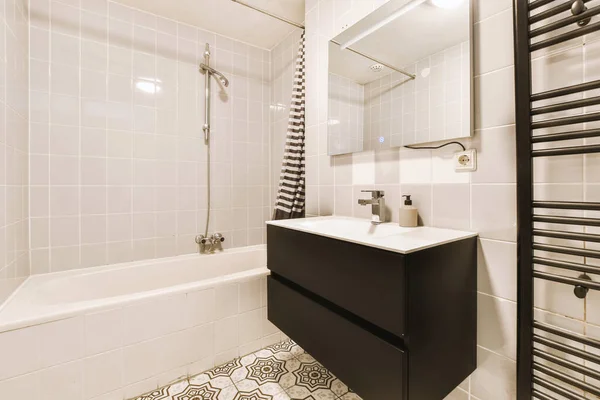 白いタイル張りの壁とモダンなバスルームでガラスのドアとシャワーボックスの近くに位置ミラーときれいな浴槽とシンク — ストック写真