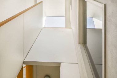 Minimalist iç tasarımı olan modern lüks dairenin ikinci katına çıkan ahşap merdivenli beyaz koridor.