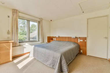 Büyük pencerelere karşı klasik koltuklu aydınlık yatak odasının içi