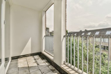 Eski tuğla binaların panoramik manzarası. Küçük balkondan park yerleri ve ağaçlar.