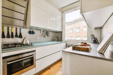 Minimalist tarzı beyaz mobilyalı, lavabolu ve sobalı bir ev mutfağı.