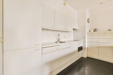 Minimalist tarzı beyaz mobilyalı, lavabolu ve sobalı bir ev mutfağı.